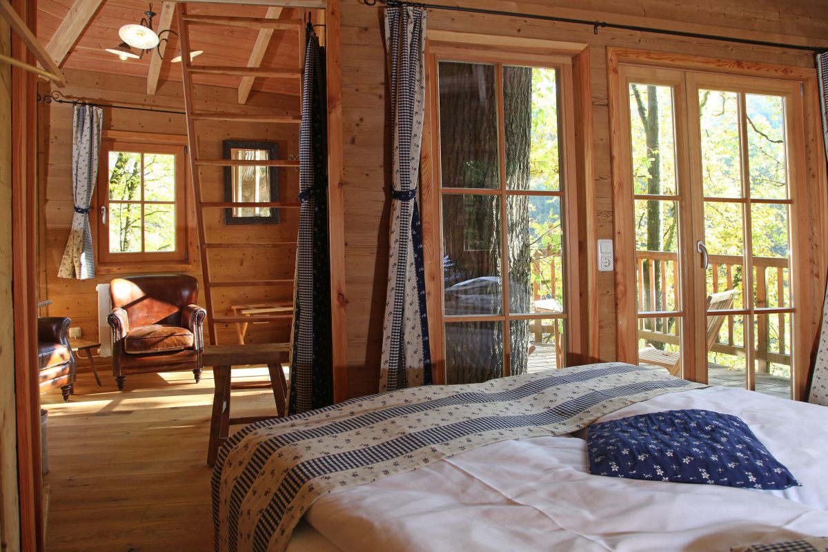 Baumhaus innen, Blick vom Bett in das Wohnzimmer und auf die Terrasse.