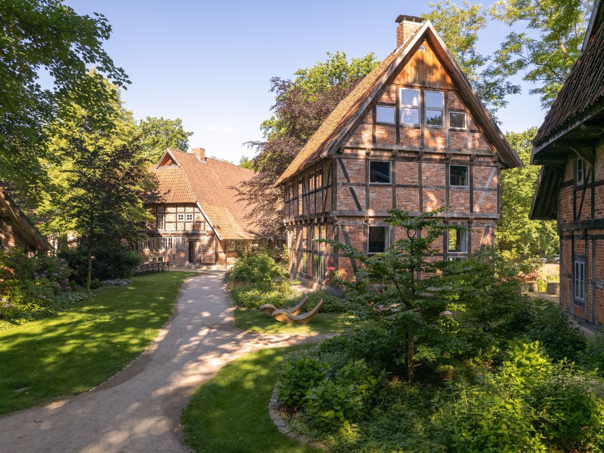 Historische Fachwerkhäuser im Biohotel WildLand, inmitten leuchtend frischgrüner Landschaft.