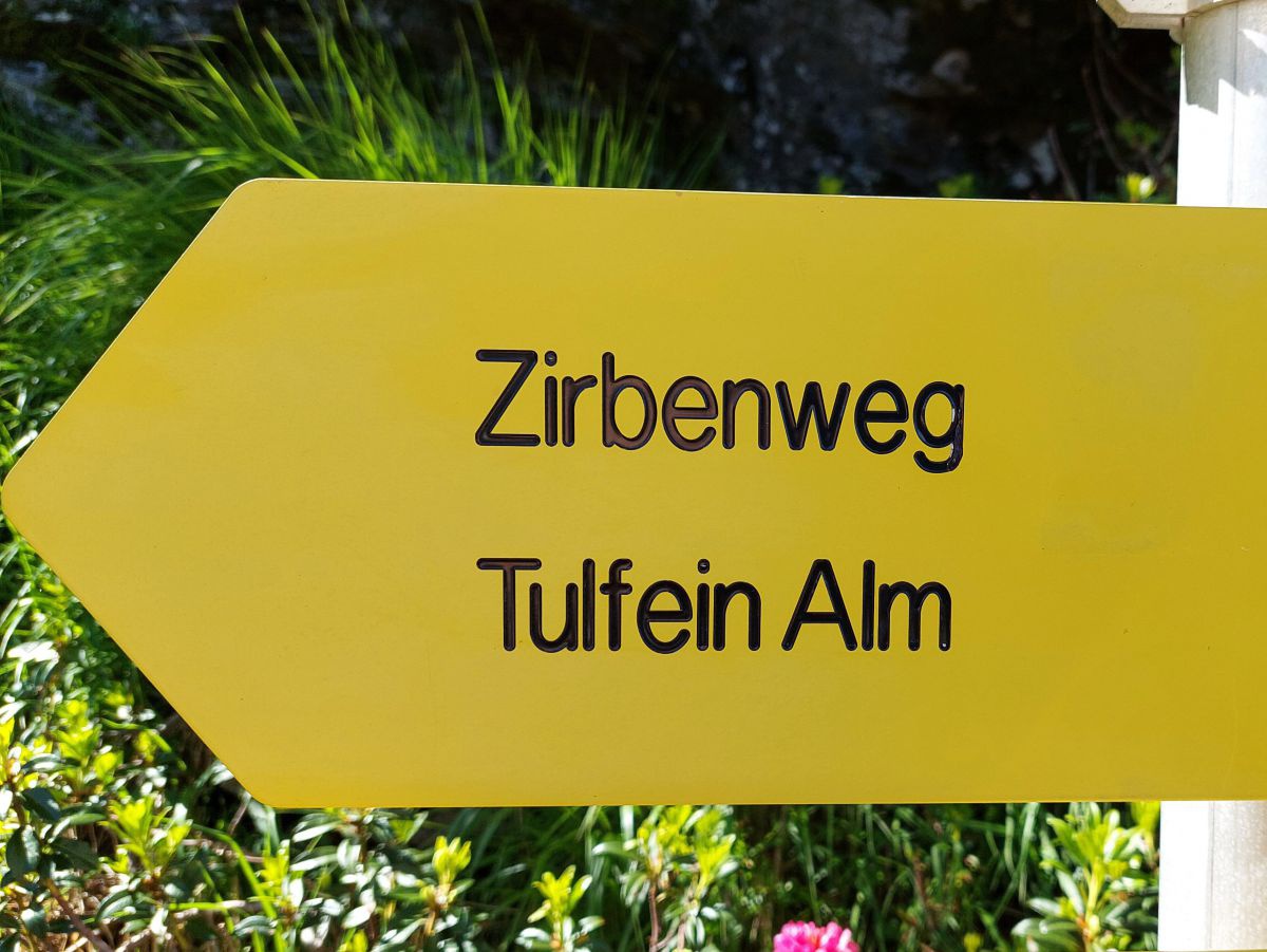 Gelbes Hinweisschild Zirbenweg Tulfein Alm.