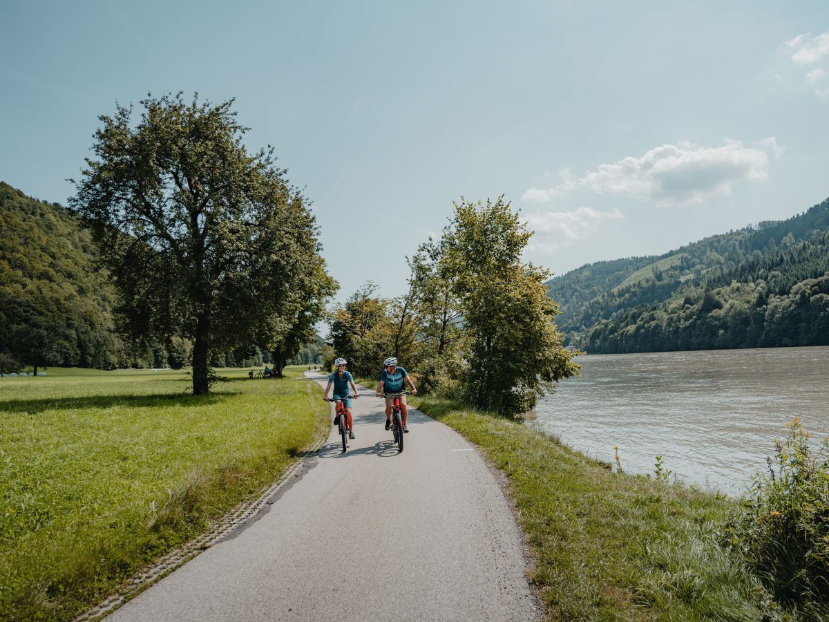 2 Radfahrende am Radweg, daneben die Donau.