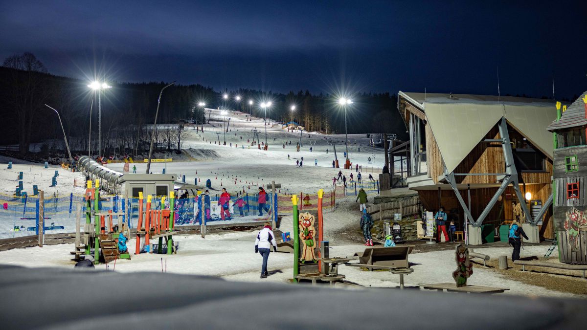 Wexl-Arena am Abend mit Flutlicht. Viele Leute tummeln sich im Schnee.