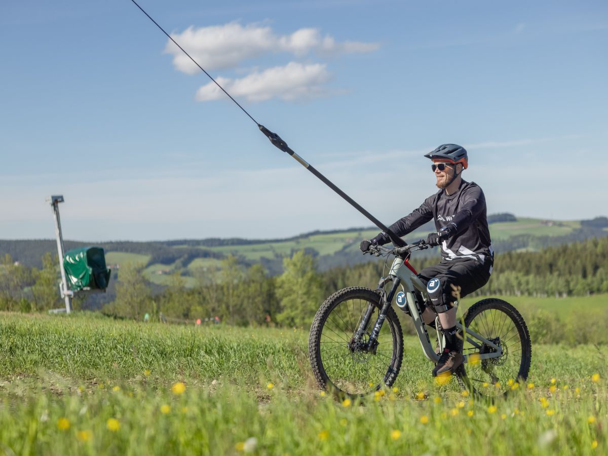 Radfahrer fährt mit Schlepplift hoch.