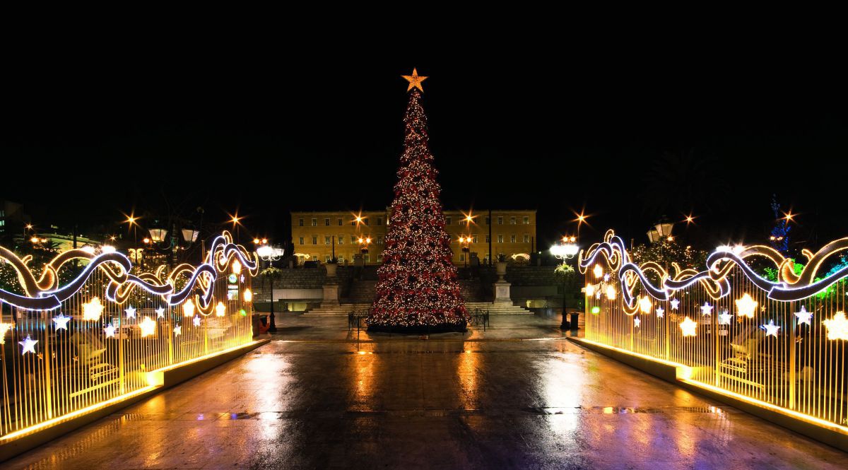 Ein Hauptplatz bei Nacht. Im Zentrum steht ein geschmückter Weihnachtsbaum, links und rechts Festbeleuchtung in Form von wogenden Wellen.