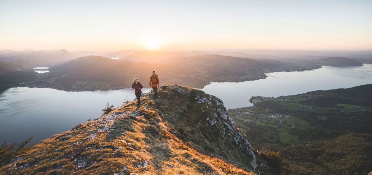 Mann und Frau auf einem Felsvorsprung mit Blick auf den Attersee.