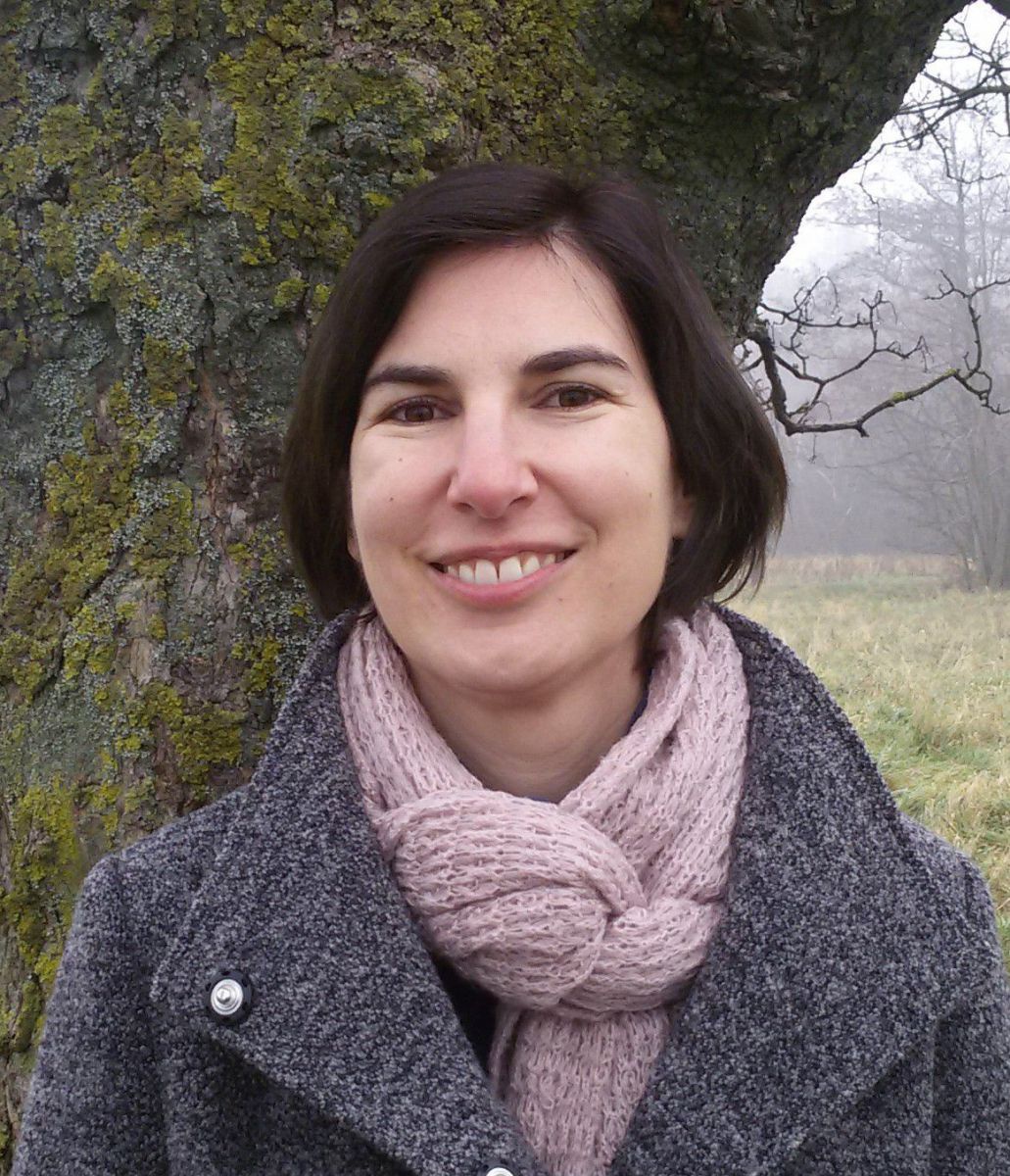 Portraitfoto in der Natur vor einem Baumstamm.