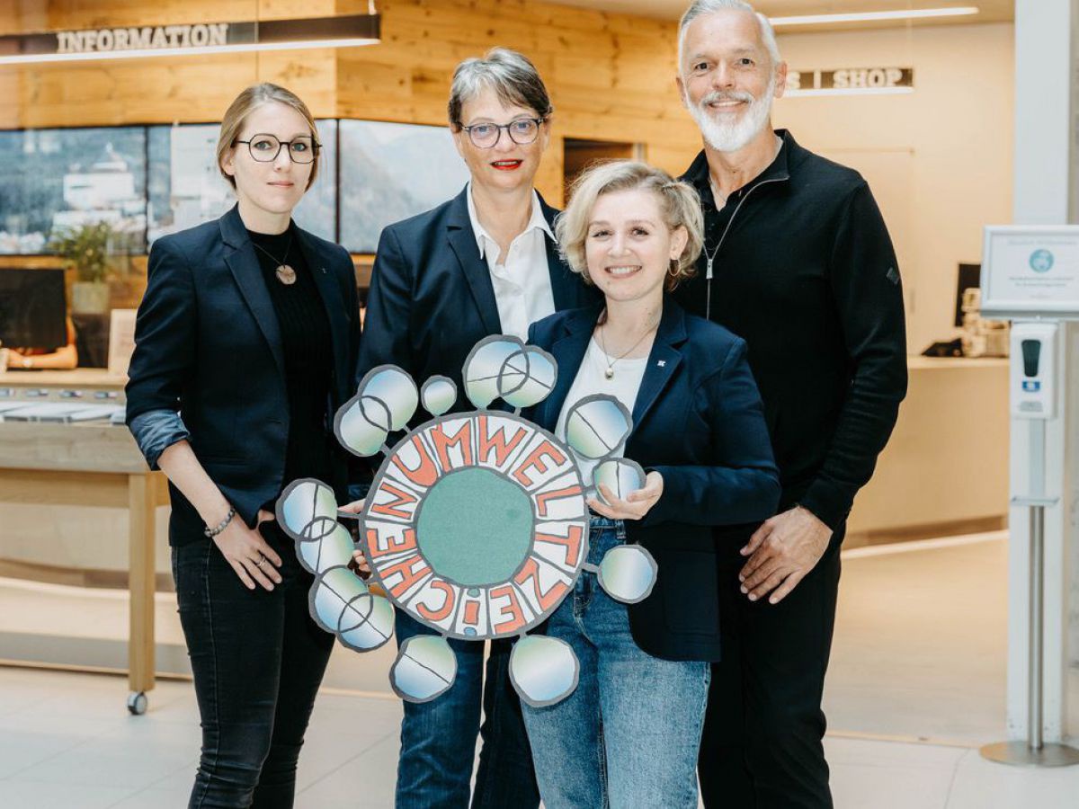 Vier Personen halten ein Umweltzeichen Logo in der Hand.