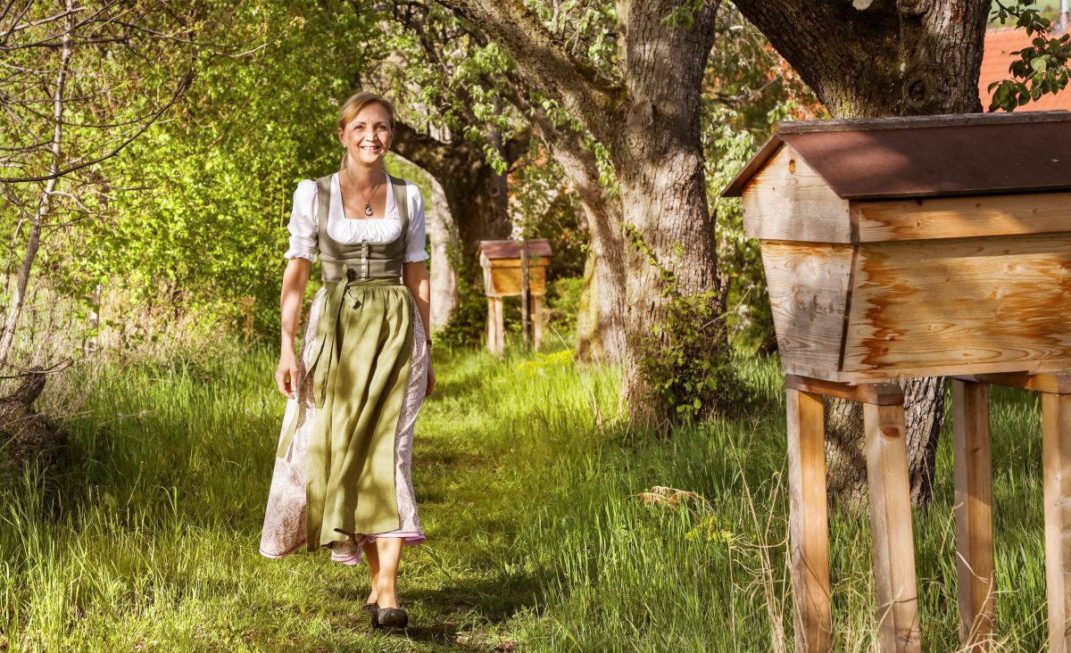 Frau in Tracht geht über eine Wiese.