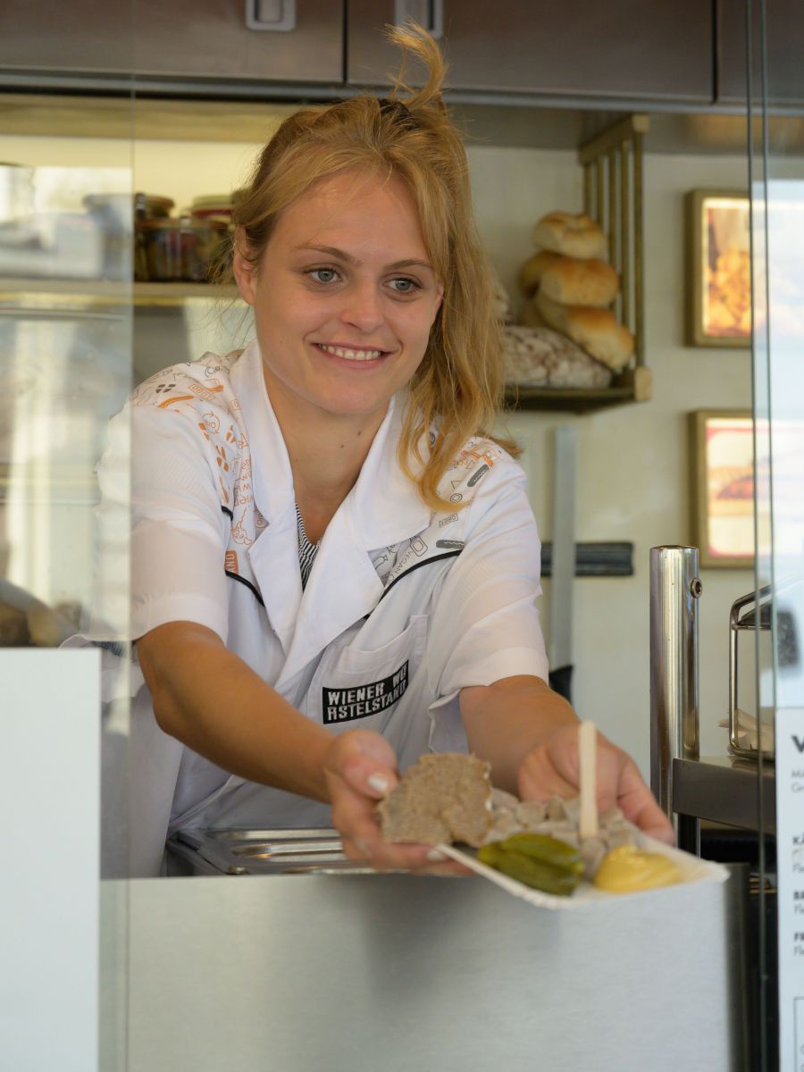 Frau serviert Würstel mit Senf.