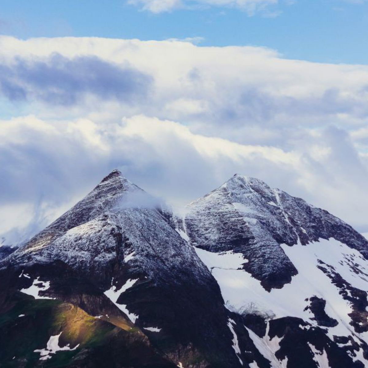 Die zwei Gipfel des Großglockner, teilweise wolkenverhangen und schneebedeckt.