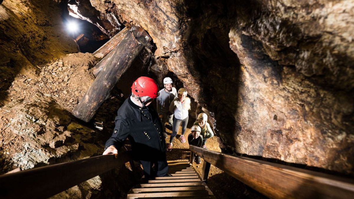 Eine Gruppe bei der Führung durch ein Bergwerk. Erwachsene wie Kinder tragen Helme.