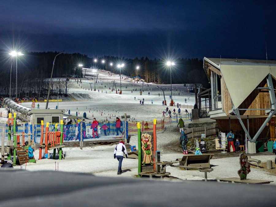 Wexl-Arena am Abend mit Flutlicht. Viele Leute tummeln sich im Schnee.